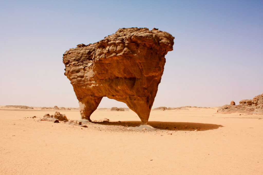 Massive, uniquely shaped rock formation rising from a desert landscape under an open sky