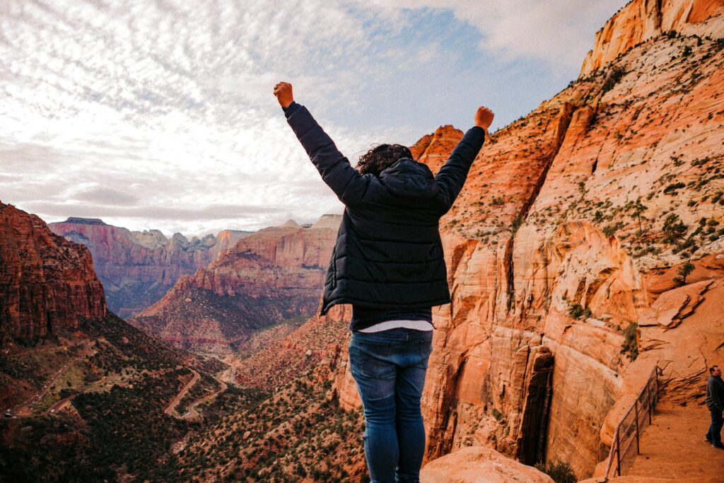 Man standing before a dramatic rocky landscape, wide natural view suggesting awe and perspective