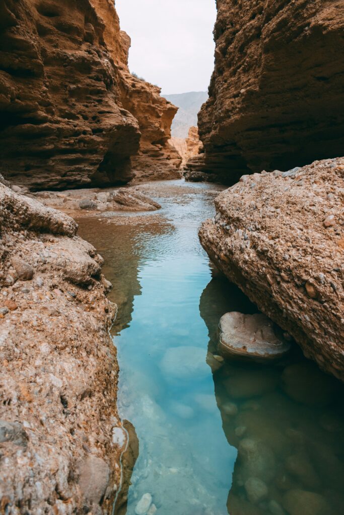 Clear water flows between canyon walls like a spring, surrounded by rock formations that suggest depth, calm, and inner flow