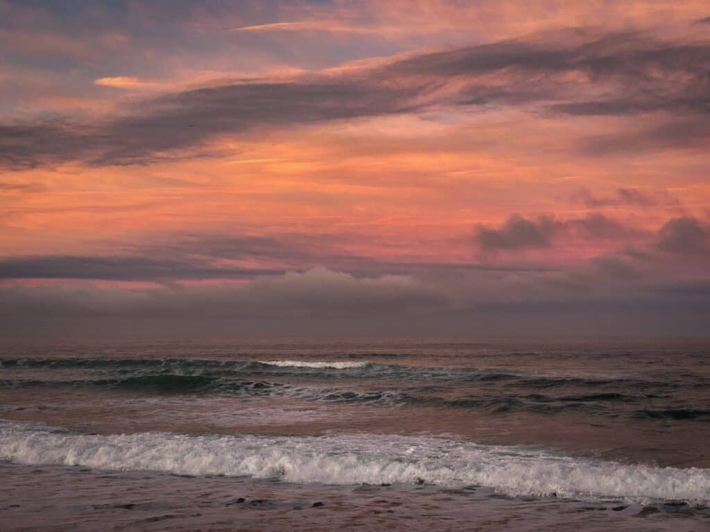 peaceful ocean waves under a pink and orange sunset sky