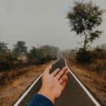 Winding road through blurred landscape, outstretched hand, motion-filled scene symbolizing journey and freedom