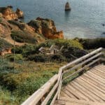  Wooden staircase leading down a mountain cliff toward the sea with expansive ocean and sky view