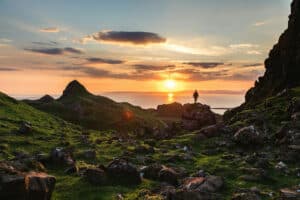  A man standing on layered green mountains at sunset symbolizes depth and reflection in clinical hypnosis in Arlington, VA