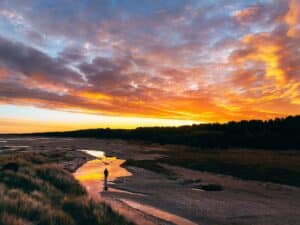 Sunset over water with a man at the riverbank, you do not have to let grief go, therapy for grief and loss in Arlington, VA 