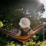  A woman resting in a hammock among trees, creating a peaceful and restorative setting.