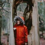  A young boy standing inside a hollow tree trunk symbolizes exploration, safety, and imaginative refuge.