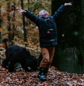  A young boy playing with dried leaves, expressing curiosity, creativity, and connection to the natural world.