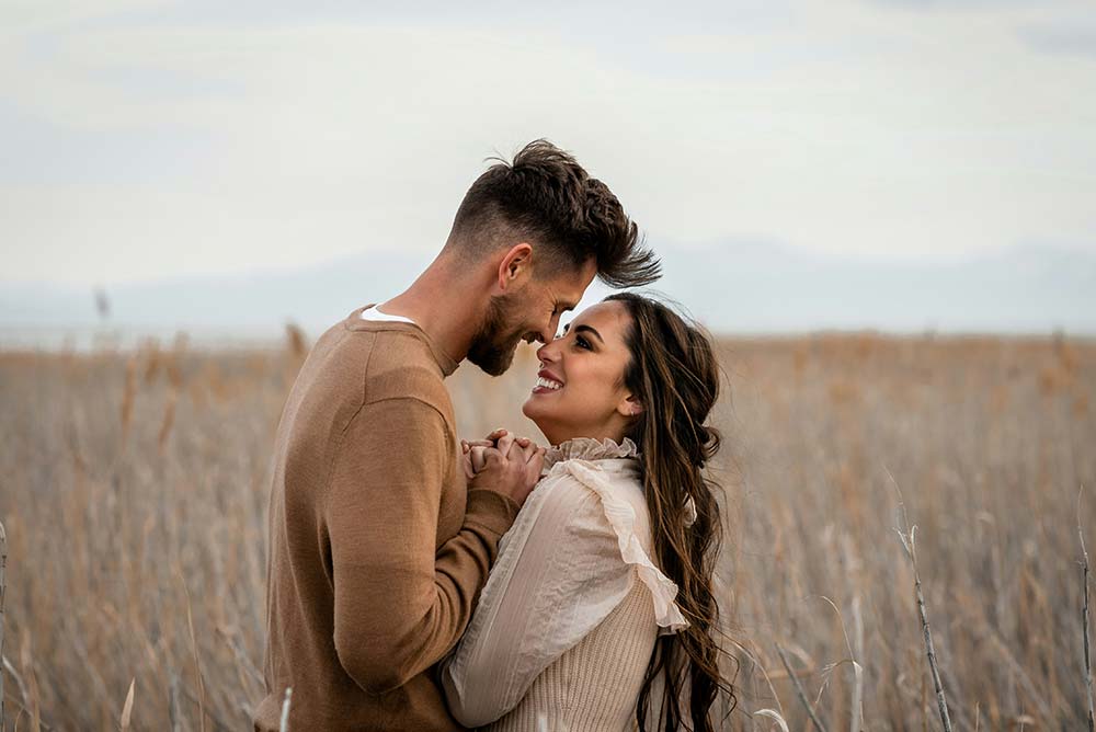 A couple looking at each other lovingly in a field.
